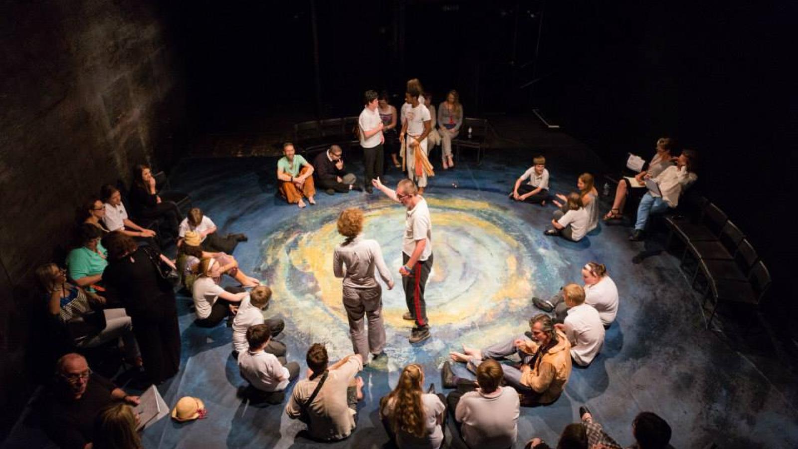 Actors perform The Tempest for children surrounding them in a circle on the floor.